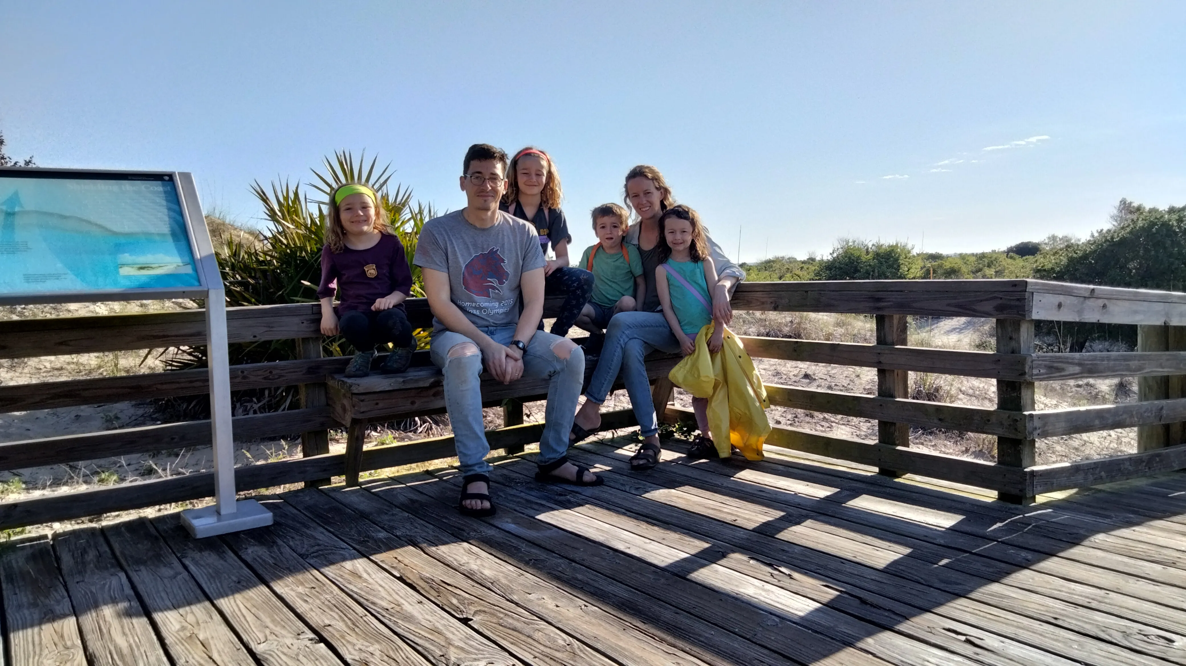 My family sitting on a bench on a boardwalk to the dunes on the east side of the island.