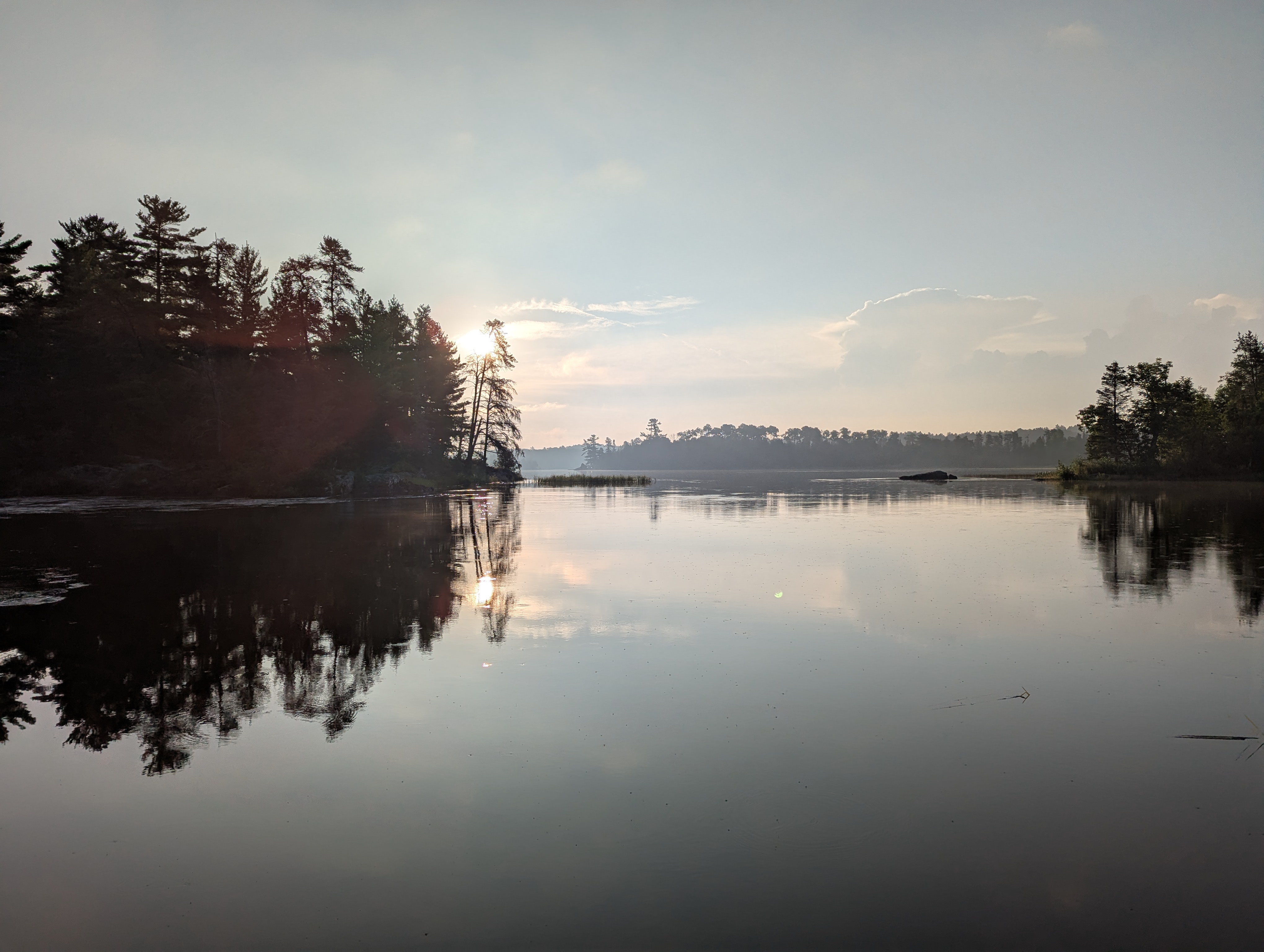 A bright sunrise over still water.