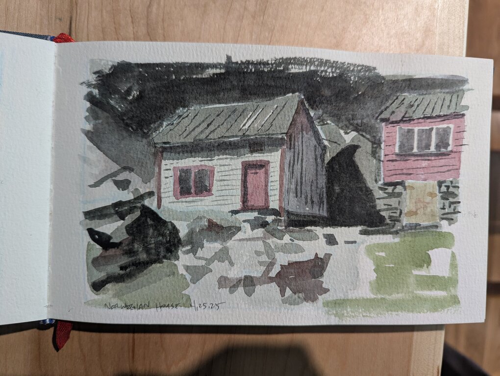 A small white clapboard house set against rocks.