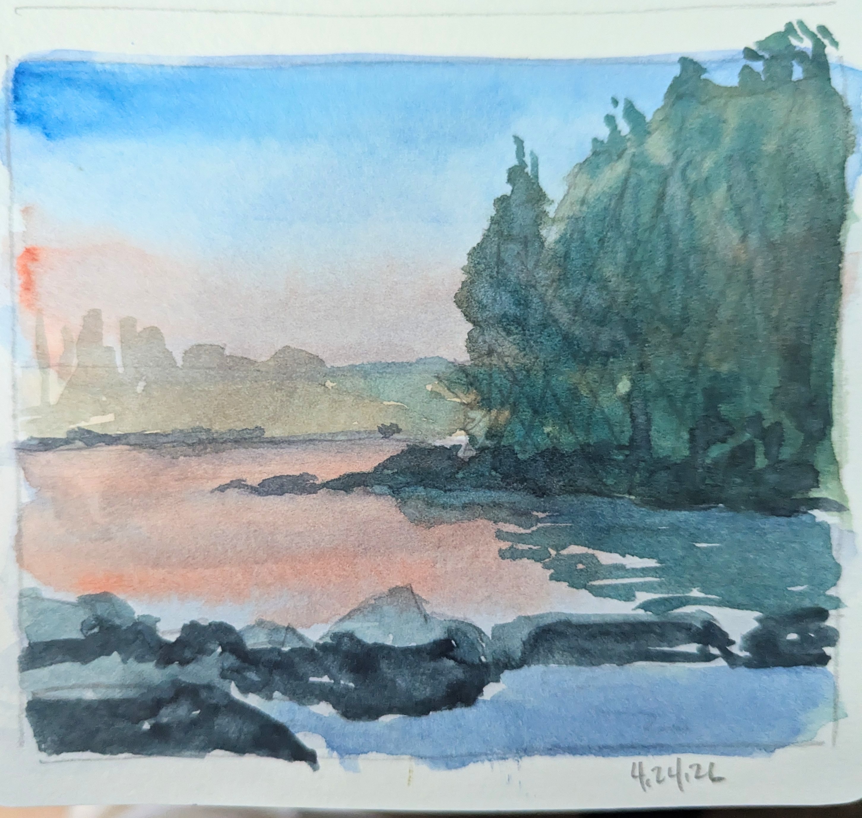 A watercolor painting of a lake. Trees are wrapping a small inlet in the foreground at sunset. Since it is a sketch, you can see some pencil marks on the page.