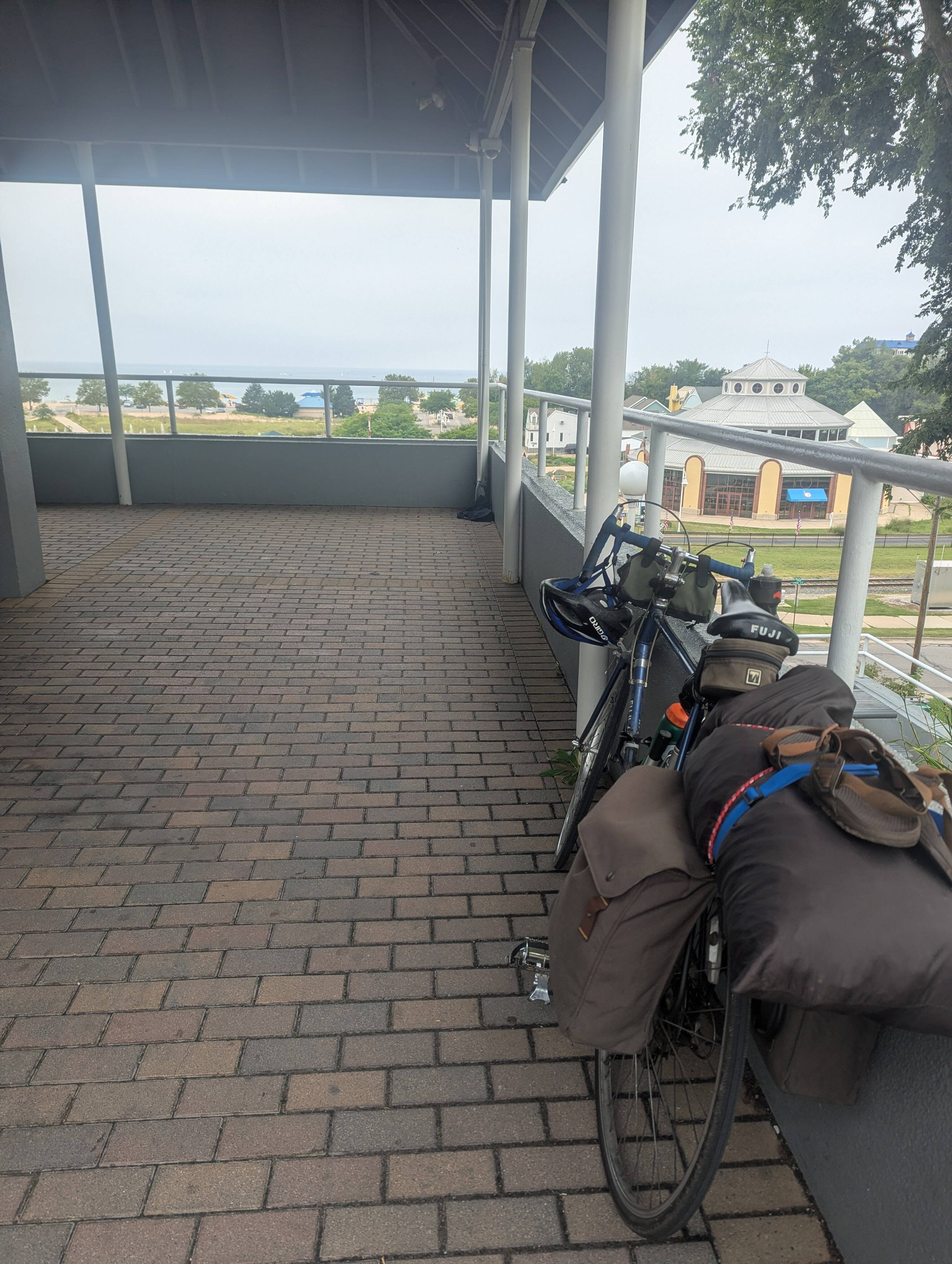 The bicycle, reloaded, leaning against a railing of a pavilion in St. Joseph, MI. Lake Michigan is in the distance. If you look very closely, you can see the sailing children again.